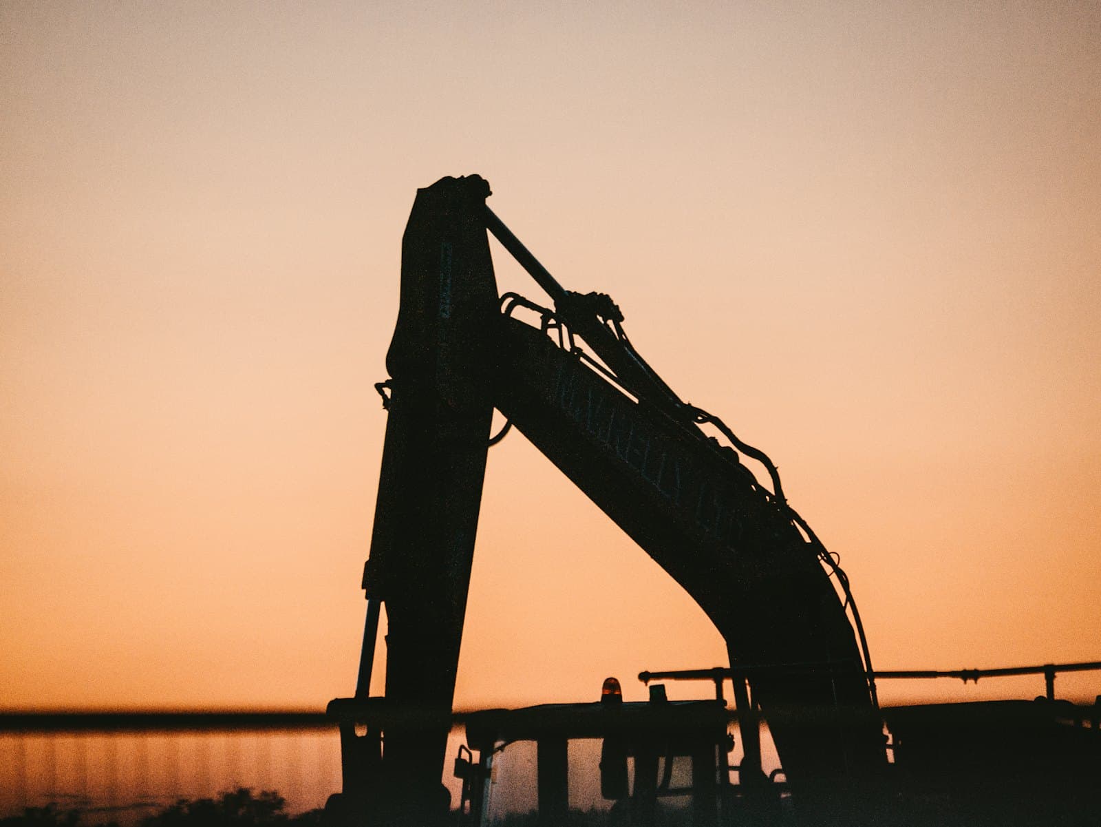 Tower crane silhouetted against a dusk sky above a high-rise under construction