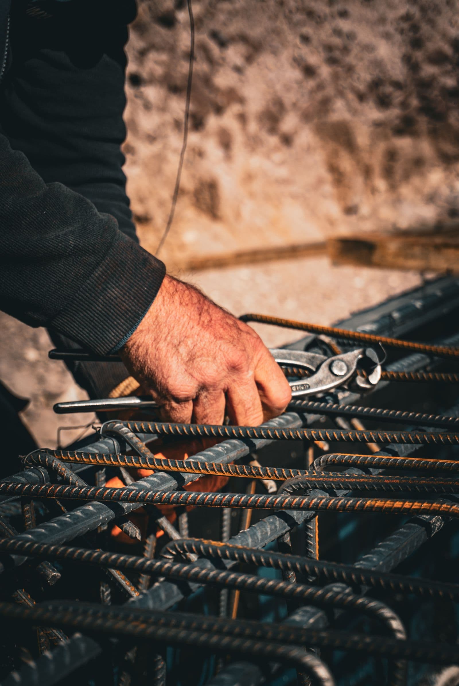 Worker in a hard hat tying rebar by hand